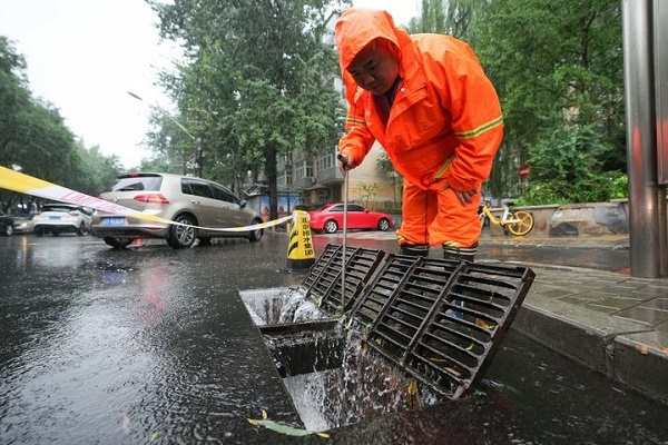 图6：7月12日，在北京市朝阳区姚家园路，北京市排水集团的一名工作人员在查看排水口的排水情况.jpg